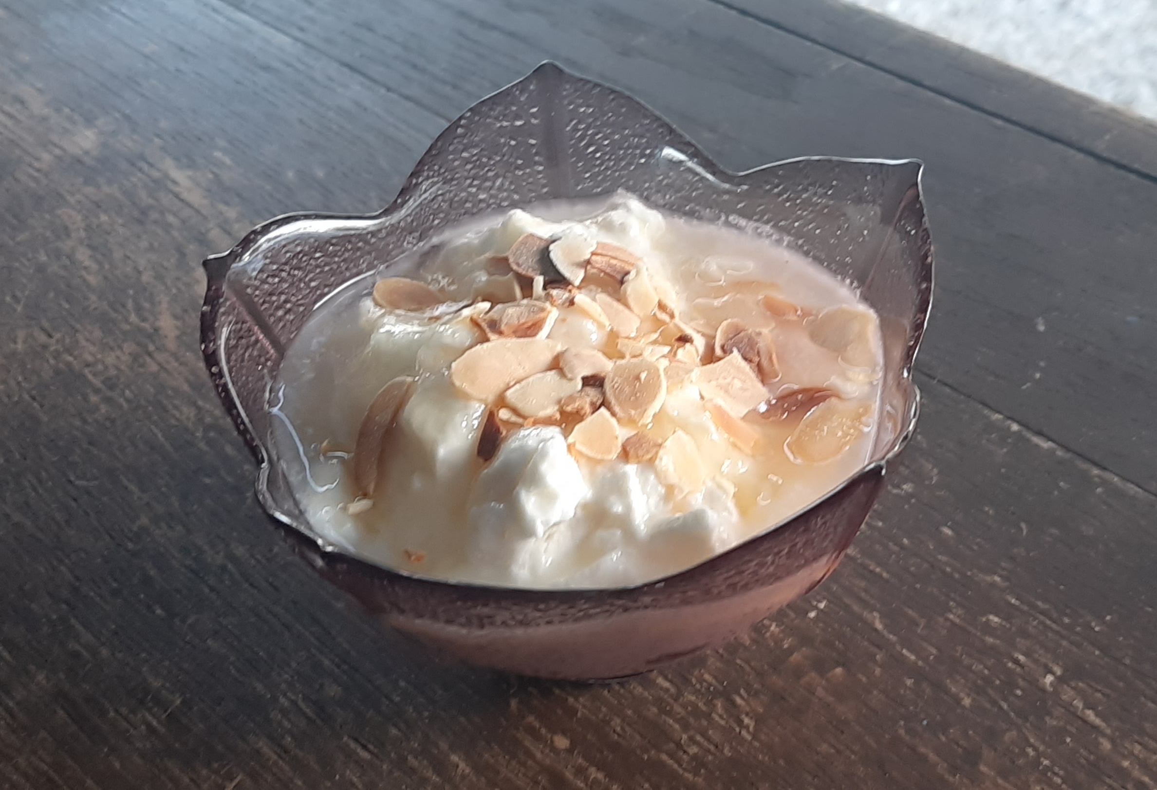 Photo d'une coupe contenant de la faisselle du miel et des amandes